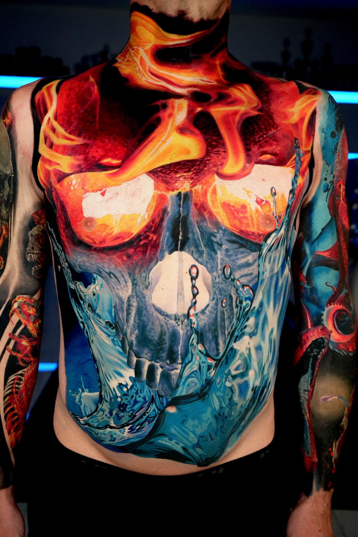 Colour chest and stomach piece of a skull half in flames and half in ocean water
